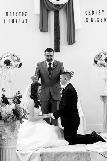 Pastor blessing young couple during baptist wedding ceremony